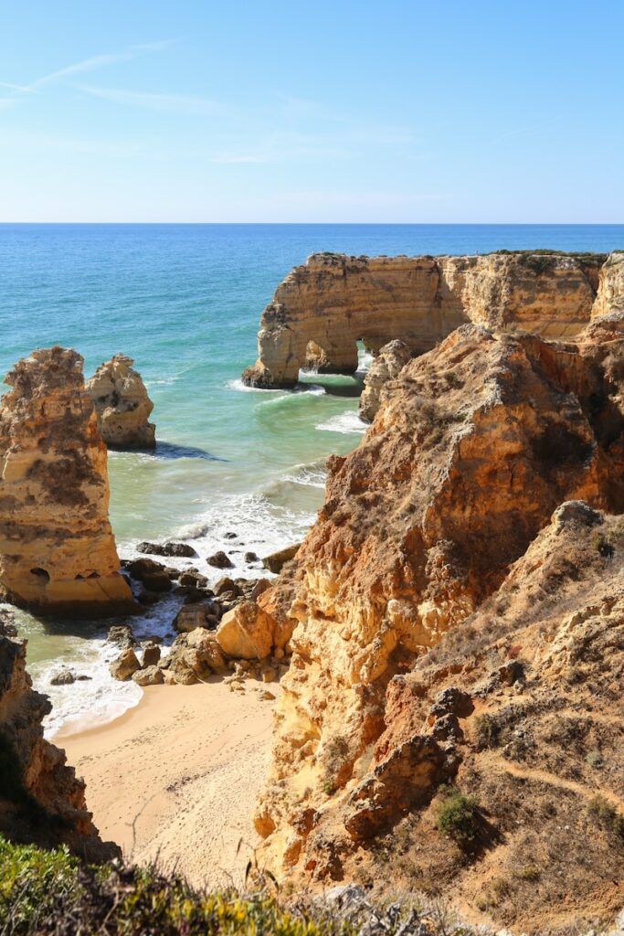 a view of a beach with a rock formation in the water